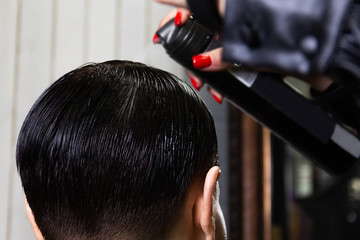 Fototapeta premium Makeup artist does hairstyle to a girl with beautiful black short hair. Beauty and fashion industry. Gel polish for hair. Shine and glow