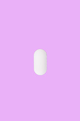 Oblong medical pill on a pink background.