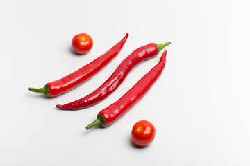 Juicy red hot chili peppers with cherry tomatoes on a branch on a white background