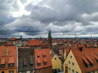 Fototapeta na wymiar View from the high tower of the old part of the modern city, the beautiful roofs of brick shades and the sky before a thunderstorm.