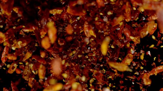 Dried chilli peppers explosion on black background. Shot with high speed cinematic camera. Super Slow Motion at 1000 fps.