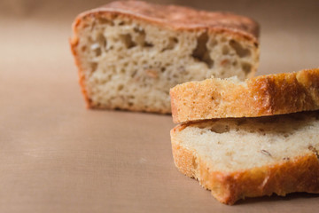 Homemade rye-wheat yeast-free bread with live sourdough. Two slices of rye-wheat bread close-up on a beige linen cloth with the remaining loaf of bread in the background with soft focus