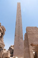 Ancient ruins of Karnak temple in Egypt in the summer, Obelix and statues of Ramses II at the first pylon of the Luxor Temple (1279-1213 BC)