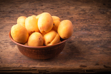Ripe apricots berries in a clay bowl on a wooden table