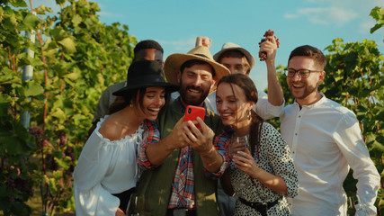 Group of attractive young friends laughing of fun content on smartphone hanging out staying at...