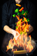 Chef with wok sauteing and flaming vegetables © Icruci