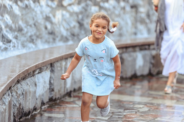 Happy beautiful girl running through the spray of water. © lialia699