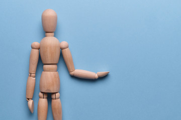 Wooden mannequin abstractly holds an object on a blue background.