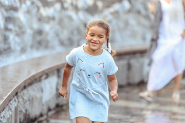 Naklejka premium Happy beautiful girl running through the spray of water.