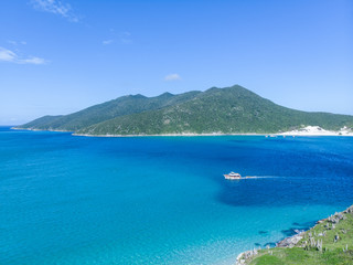 Vista de drone de barco entre ilhas no mar paradisíaco de Arraial do Cabo, Rio de Janeiro, Brasil