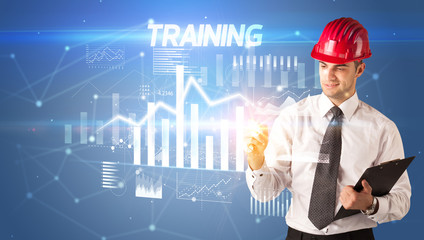 Handsome businessman with helmet drawing TRAINING inscription, architecture business plan concept