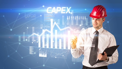 Handsome businessman with helmet drawing CAPEX inscription, architecture business plan concept