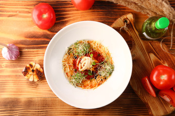 tomato soup with squid and cheese decorated with microgreen on wooden table and white wine top view