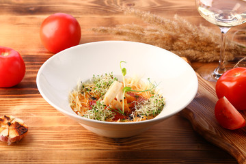 tomato soup with squid and cheese decorated with microgreen on wooden table and white wine