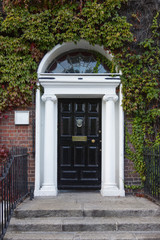 Black Georgian door surrounded by Ivy with doorknob