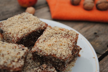Apple and Walnut Cake Cubes in a white plate, on a wooden retro background. Close up view.