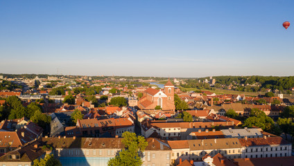 Fototapeta na wymiar Beautiful panoramic aerial view photo from flying drone on to Kaunas Franciscan Xavier Church and Kaunas City Hall with flying balloons in the background sky. Kaunas, Lithuania (series)