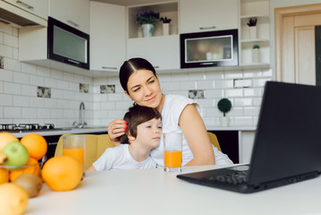 Family using a tablet pc in kitchen, mother with son happy smile, modern kitchen orange juice