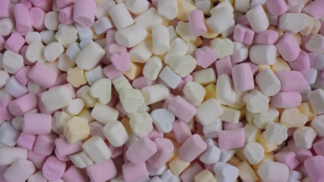 A 4K shot over the top of a lot of Marshmallows spread out on a surface. A slow panning shot off some marshmallows / confectionery.
