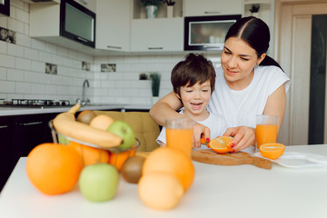 Healthy Eating. mom with baby eating fruits in the kitchen