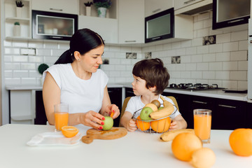 Healthy Eating. mom with baby eating fruits in the kitchen