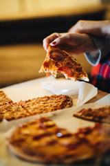 A couple of men and women eat pizza on the sofa in their living room at night while watching a movie on television. Concept of life as a couple at home.