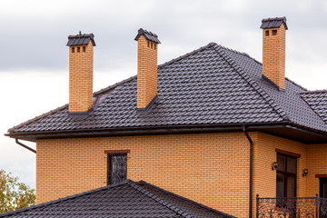 a brown rooftop of a ceramic tile with a pipe a storm drainage system, close up details of the architectural structure of brick house.