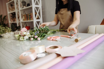 Obraz na płótnie Canvas girl florist using scissors decorates a bouquet of flowers in a flower shop