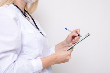 Unrecognizable female woman doctor writing a diagnosis, case medical history on a prescription board