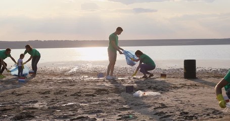 Volunteers collect garbage along the lake shore on a day off. - Powered by Adobe