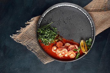 Grilled king tiger prawns with tomato sauce and arugula, beautiful serve from the chef, gray plate gray background. Bright beautiful flow of seafood, copies of space food photo