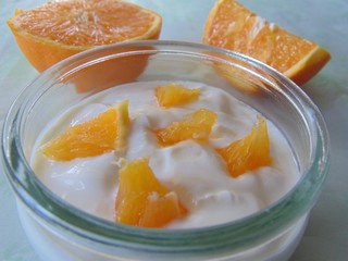 Yogurt with oranges isolated in a glass. Sour cream, yogurt with frech oranges, close up.