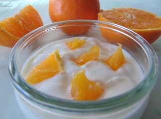 Yogurt with oranges isolated in a glass. Sour cream, yogurt with frech oranges, close up.