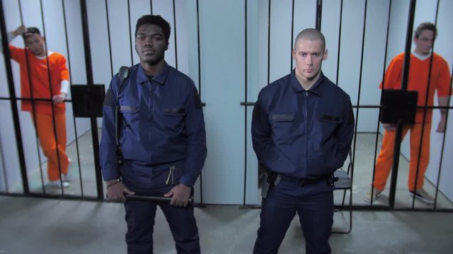 Guards stand in the background of prison cells