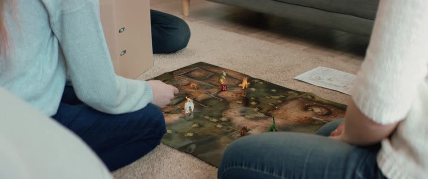 Family - father, mother and two kids playing a board game together. Stay home, quarantine. Board game is custom made for the shot. RED Dragon