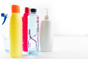 Plastic bottles of cleaning products set on white table.