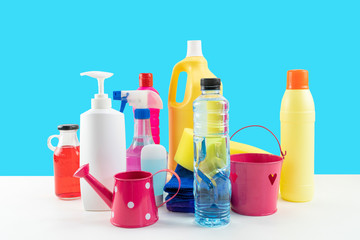 Plastic bottles of cleaning products set on white table.