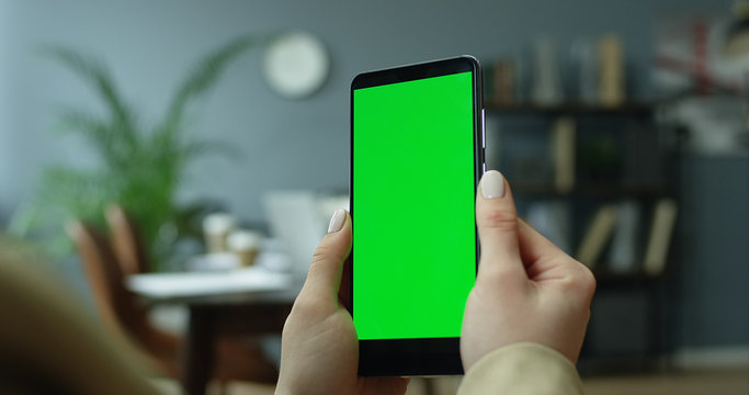Mockup image of female hands holding mobile phone with blank screen. Chroma key green screen