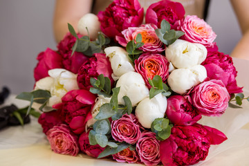 florist in black gloves creates a bouquet of red peonies