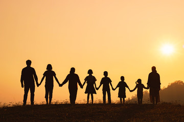 Fototapeta premium Silhouette of happy family standing on the mountain at the sunset time.
