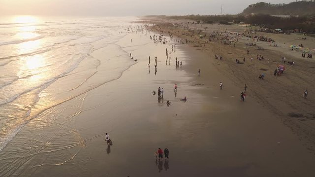 sandy beach parangtritis near ocean with big waves, people in tropical resort at sunset. Yogyakarta, Indonesia. aerial view seascape, ocean and beautiful beach. Travel concept. Indonesia, java