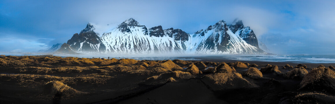 Stunning high resolution panoramic view of Vestrahorn mountain range at Stokksnes peninsula in Iceland with black sand dunes and mist at sunset.