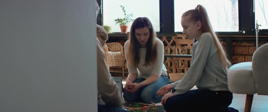 Family - father, mother and two kids playing a board game together. Stay home, quarantine. Board game is custom made for the shot. RED Dragon