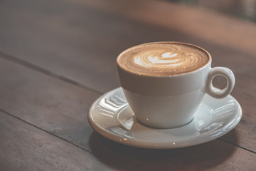 Cup of art latte or cappuccino coffee on wood table