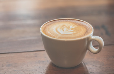 Cup of art latte or cappuccino coffee on wood table