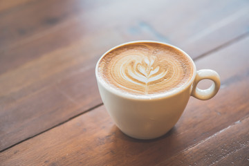 Cup of art latte or cappuccino coffee on wood table
