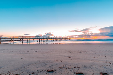 Fototapeta premium Sunrise over bridge with waves crashing take at Gold Coast Australia
