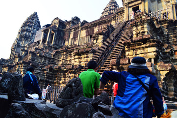 Obraz premium Travelers rest on ground seeing high wall of a temple