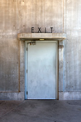 Concrete wall and white door with exit sign