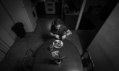 Man staying at home eating dinner alone while in quarantine during self isolation